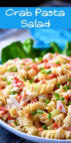 a pasta salad in a white bowl on top of a wooden table