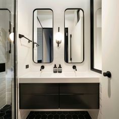 a bathroom with two sinks and mirrors on the wall next to a walk in shower