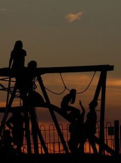 silhouettes of children playing on a playground at sunset