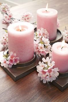 three pink candles sitting on top of wooden coasters