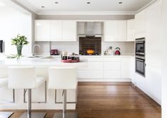 a kitchen with white cabinets and wooden floors