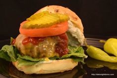 a cheeseburger with lettuce, tomato and pickle slices on it