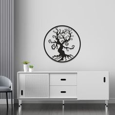 a living room with a white cabinet and a black tree wall decal on the wall