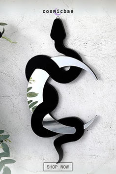 a black and white sculpture sitting on top of a wall next to a potted plant