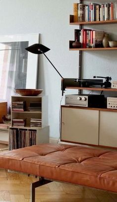 a living room with a couch, bookshelf and various items on the shelves