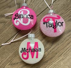 three personalized christmas ornaments on a wooden table