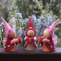 three little gnomes are standing next to some flowers