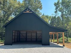 a large garage with two doors open in front of trees