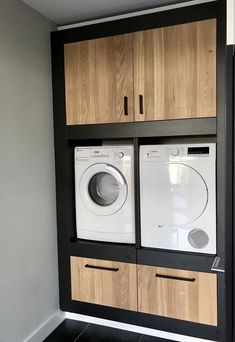 a washer and dryer in a room with wooden cabinets on the wall above them