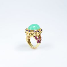 Immerse yourself in the enchanting allure of royalty with this magnificent ring. At its heart lies a luminous Chrysoprase gemstone, radiating a serene green glow. Encircling the central gem are rich purple Amethysts and vibrant Rubies, creating a dazzling display of color and brilliance. The intricate gold-plated design, inspired by regal elegance, adds a touch of sophistication and grandeur. Perfect for those who appreciate unique and luxurious jewelry, the "Royal Enchantment" ring is a stateme Green Cabochon Fine Jewelry Rings, Green Cabochon Rings Fine Jewelry, Exquisite Green Cabochon Ring, Luxury Green Domed Ring, Fine Jewelry May Birthstone Cabochon Ring, Green Dome Ring As A Gift, Fine Jewelry, Elegant Turquoise Chrysoprase Rings, Luxury Green Opal Ring For Gift, Vintage Gold Ring