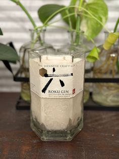 a candle that is sitting on a table next to some potted plants in vases