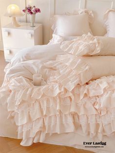 a white bed with ruffled sheets and pillows