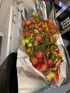 a piece of tin foil covered in vegetables and other food on top of a counter