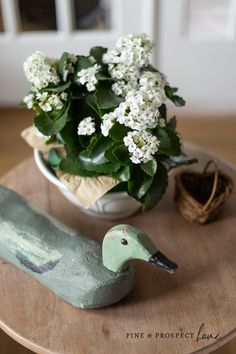 a bird figurine sitting on top of a table next to a potted plant