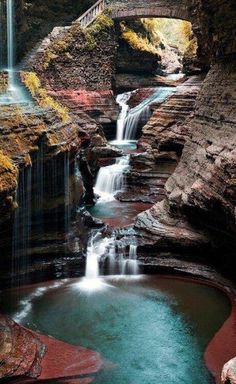 a small waterfall with a bridge over it