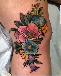 a woman's thigh with flowers and leaves on the side by tattoo artist person