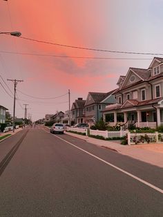 an empty street with houses and cars on it at sunset or sunrise in the city