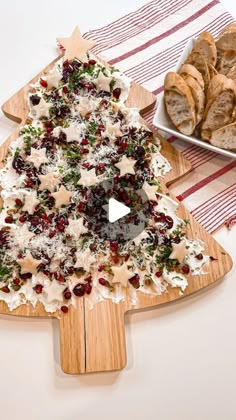 a wooden cutting board topped with a christmas tree cut out of cheese and cranberries