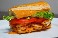 a sandwich with shrimp, tomatoes and lettuce