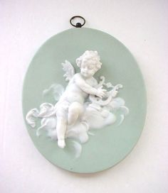 a white angel sitting on top of a green plate next to a keychain