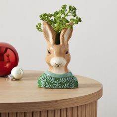 a rabbit planter sitting on top of a wooden table next to christmas balls and ornaments