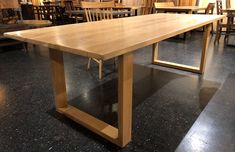 a large wooden table sitting on top of a black floor next to tables and chairs