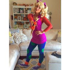 a woman is dressed up in her living room and posing for the camera while holding a carrot