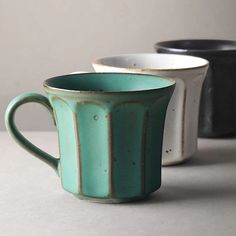 three coffee mugs sitting next to each other on top of a white countertop