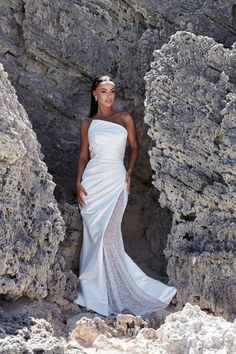 a woman in a white dress standing on rocks