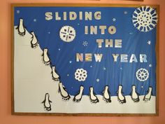 a bulletin board with penguins and snowflakes hanging on it's side in front of a wall