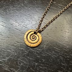 Spirals are a common shape found in the natural world: the path of draining water, weather patterns like hurricanes, vine tendrils, galaxies, shells, the horns of various animals... It was easy to find inspiration to create these!! Measuring 5/8" in diameter, this carved brass spiral is very lightweight and makes a great everyday necklace!Set on a 16"/18" Oxidized brass chain. Spiral Brass Jewelry, Handmade Spiral Nature-inspired Jewelry, Unique Spiral Bronze Jewelry, Unique Bronze Spiral Jewelry, Spiral Necklace, Weather Patterns, Everyday Necklace, Brass Necklace, Brass Chain