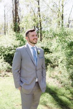 a man in a gray suit and blue tie smiles at the camera as he stands outside