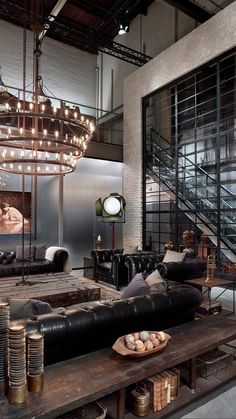 an industrial living room with black leather couches and large chandelier hanging from the ceiling