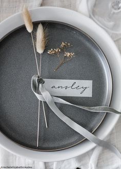 an empty plate with a name tag and some dried flowers on the side, tied to it