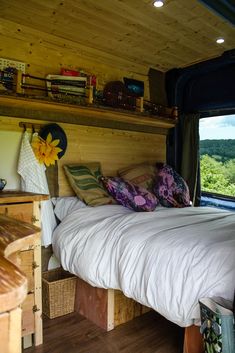 a bed in a room with wooden walls and shelves on the wall next to it