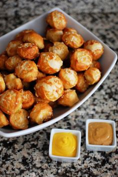 some food is in a white bowl on a table next to small bowls with dipping sauces