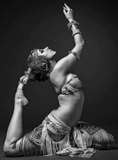 a woman in belly dance poses with her arms up and legs spread out to the side