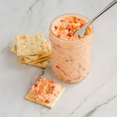 a glass jar filled with food next to crackers on top of a white counter