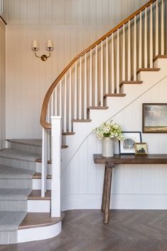 there is a vase with flowers sitting on the table next to the stairs in this house