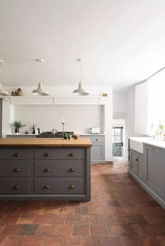 a kitchen with grey cabinets and wooden counter tops, along with an island in the middle