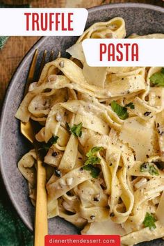 pasta with mushrooms and parsley in a white sauce on a gray plate next to a yellow fork