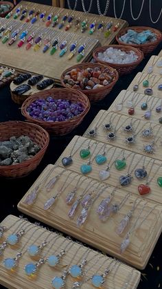 many necklaces are displayed on wooden trays with beads and stones in baskets next to each other