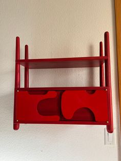 a red shelf is hanging on the wall