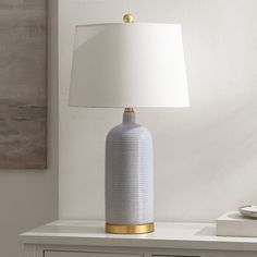 a white table lamp sitting on top of a dresser