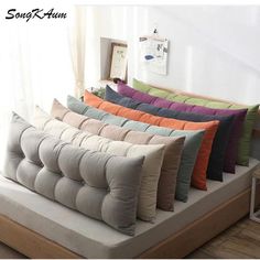 a bunch of pillows sitting on top of a couch in front of a white wall