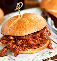 a pulled pork sandwich sitting on top of a white plate with a toothpick in it