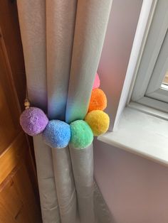 the rainbow colored pom - poms are hanging from the curtain in front of the window