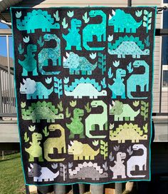 a quilt hanging on the side of a house with an elephant and giraffe design