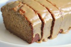 a loaf of cake with frosting sitting on top of a white plate next to a fork