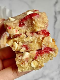 four pieces of dessert on a plate with nuts and cranberry toppings in the middle